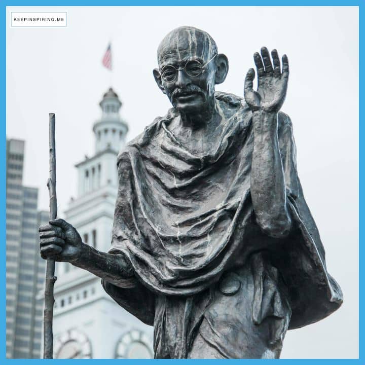 A statue of Mahatma Gandhi holding up his hand.